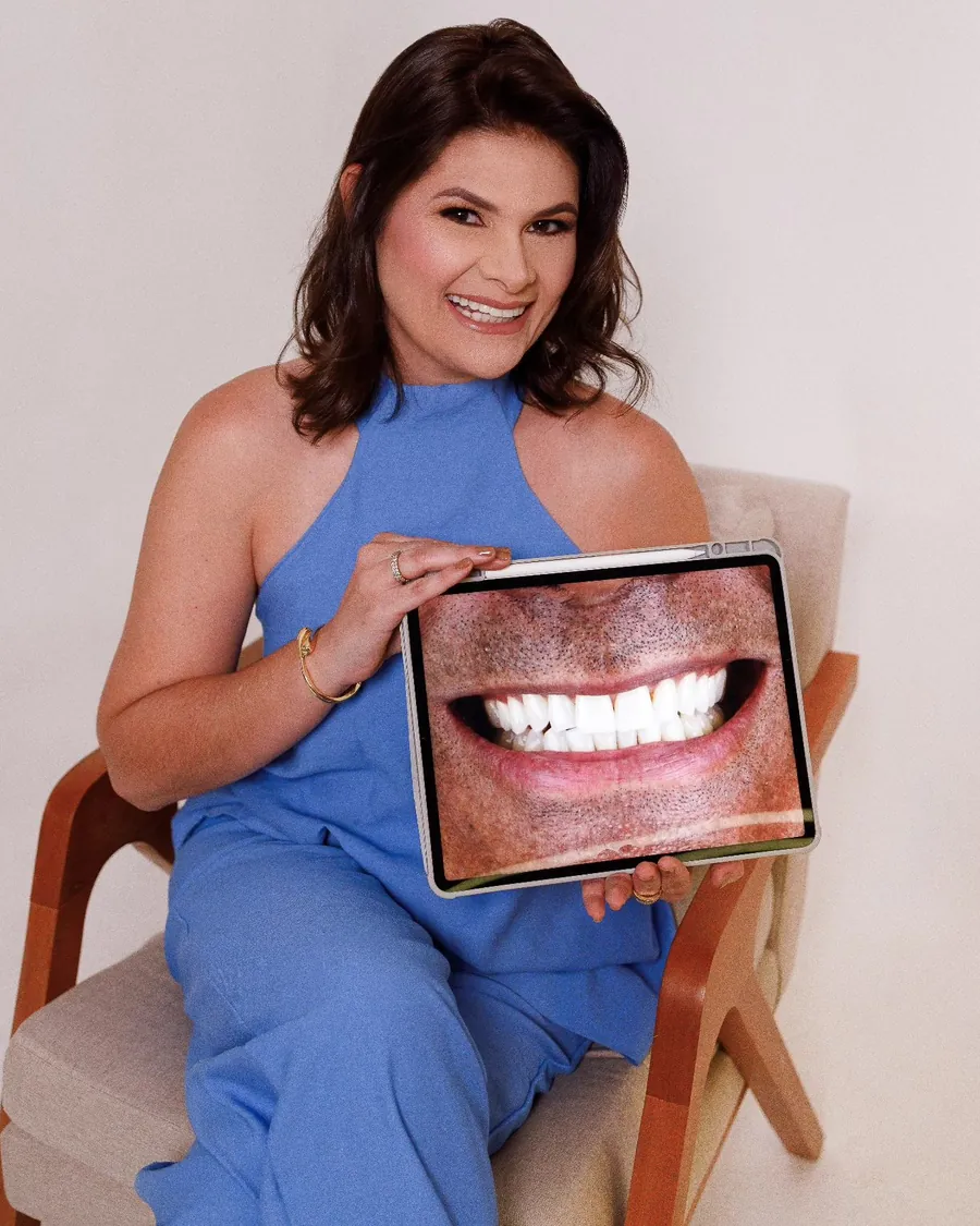 Drª Clarissa Braz sentada, segurando um tablet com a foto de um sorriso